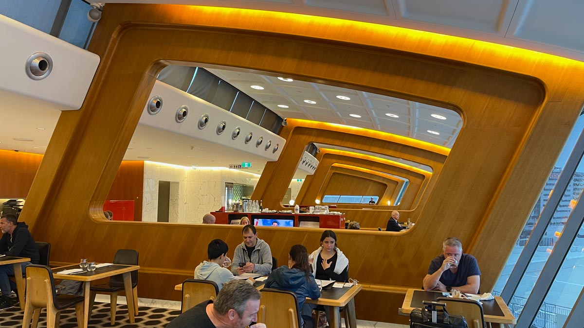 a group of people sitting at tables in a room with a wall and ceiling