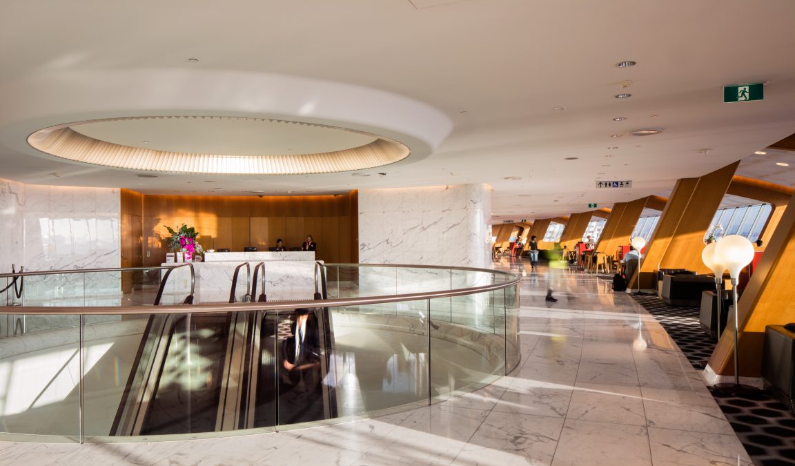 a large white and marble room with a staircase and escalator