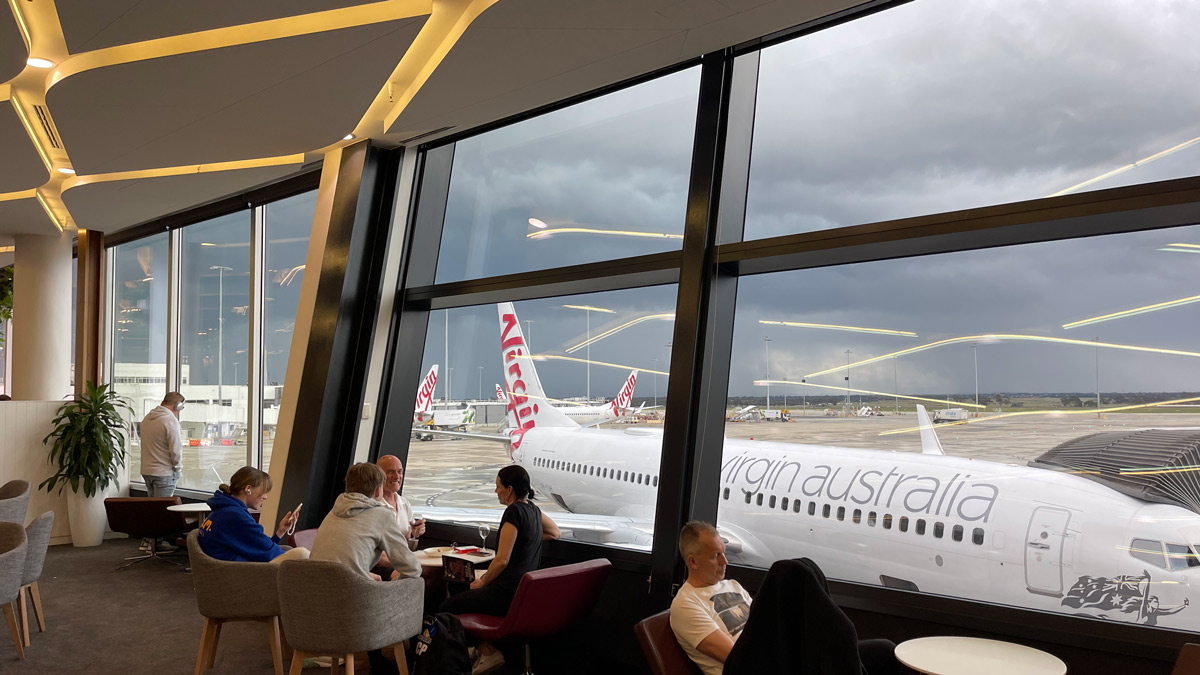 people sitting in a room with large windows and airplanes