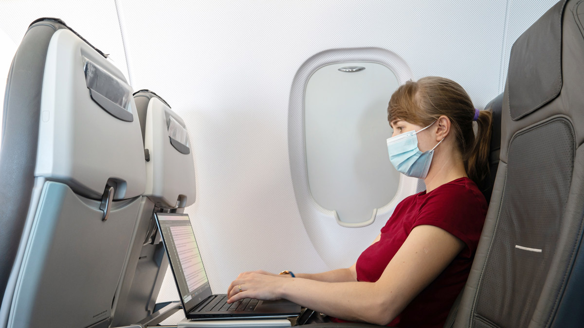 a woman wearing a mask while using a laptop