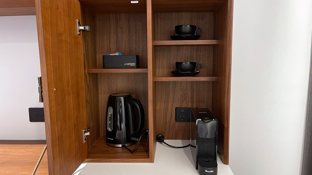 a cabinet with a coffee pot and cups on it