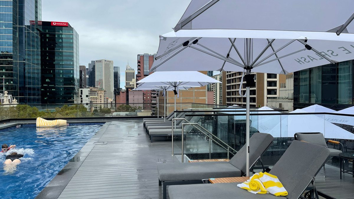 a pool with umbrellas and chairs on a rooftop
