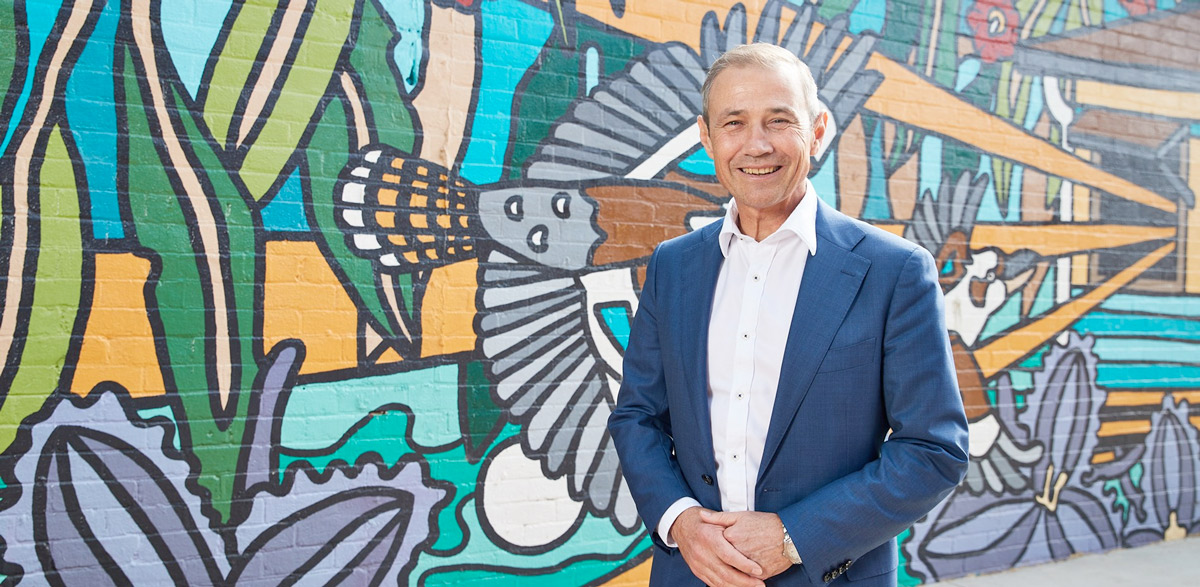 a man in a suit standing in front of a mural