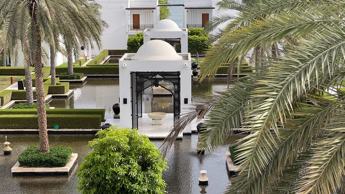 a white building with a dome roof and a pool of water