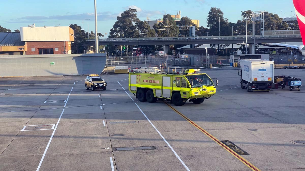 a yellow fire truck and a car on a runway