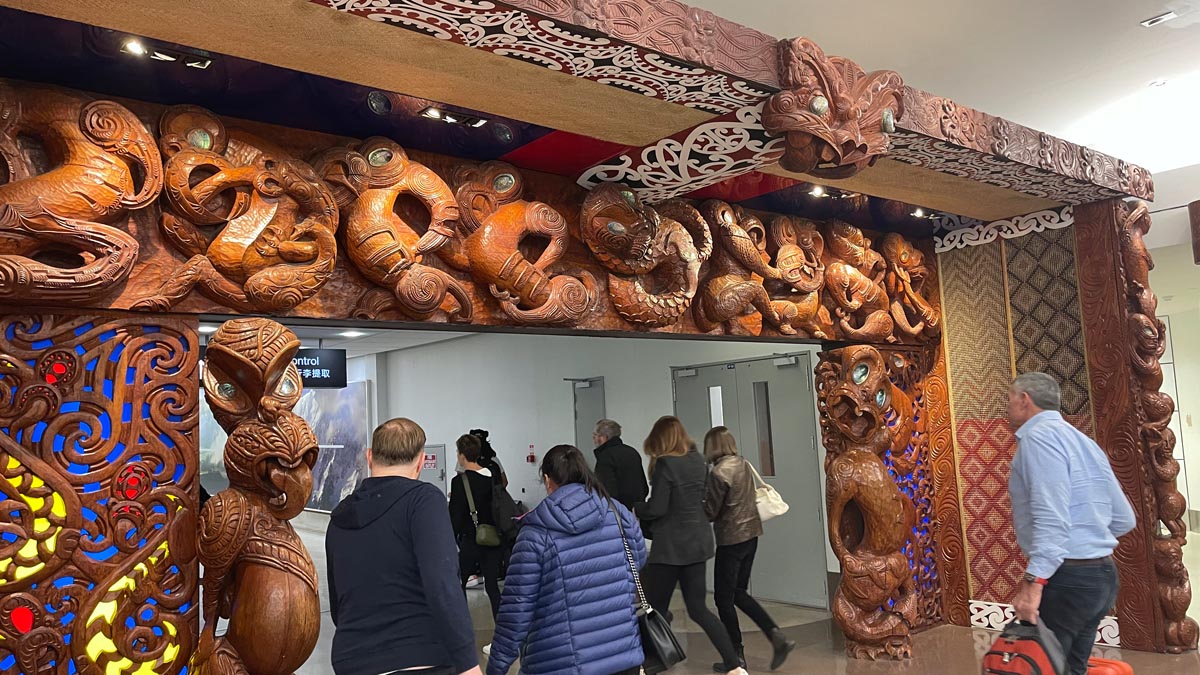 people walking past a large carved archway