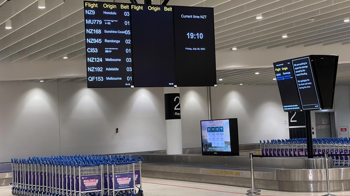 a luggage carousel with screens and luggage carts