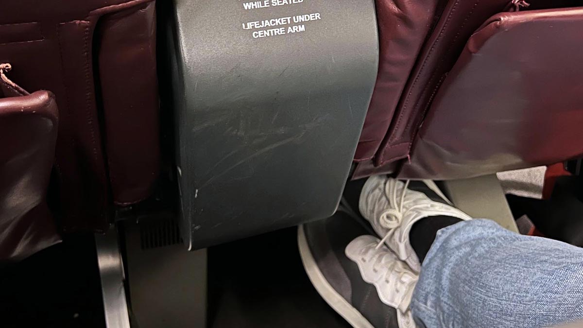 a person's feet in white shoes and a grey object on a plane