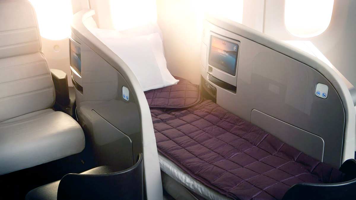 a bed with a purple blanket and a tv on the back of a plane
