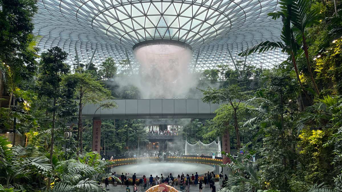 a large glass dome with a large fountain and people in it