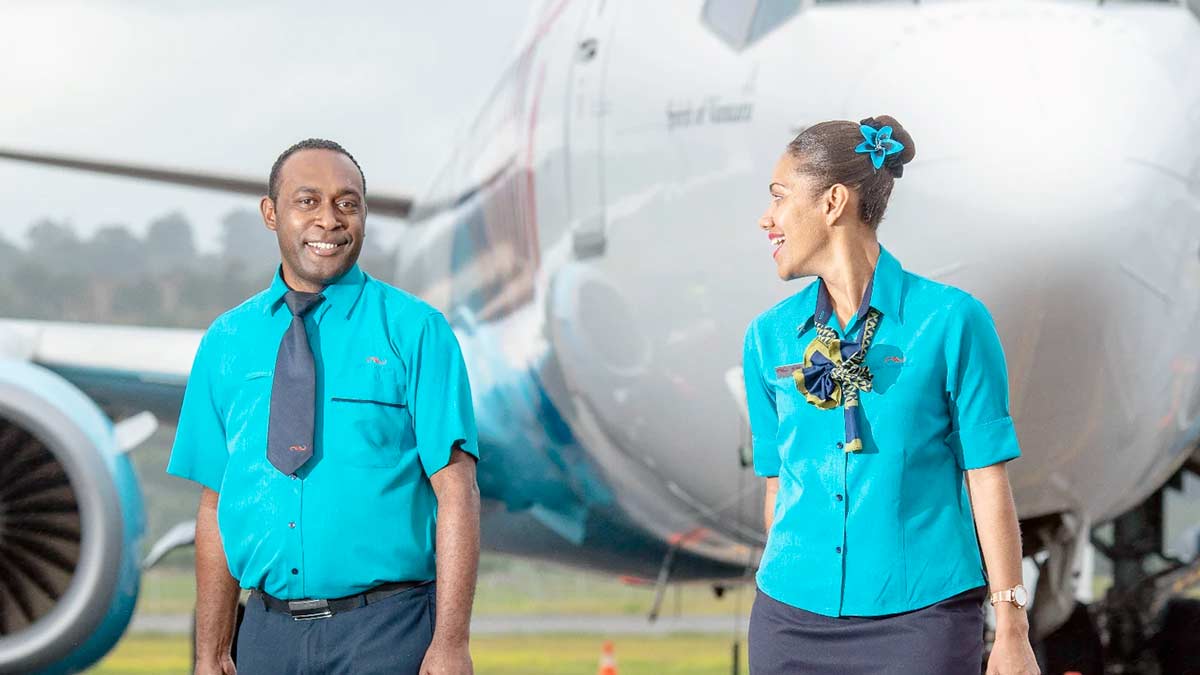 a man and woman in blue shirts and ties standing next to an airplane