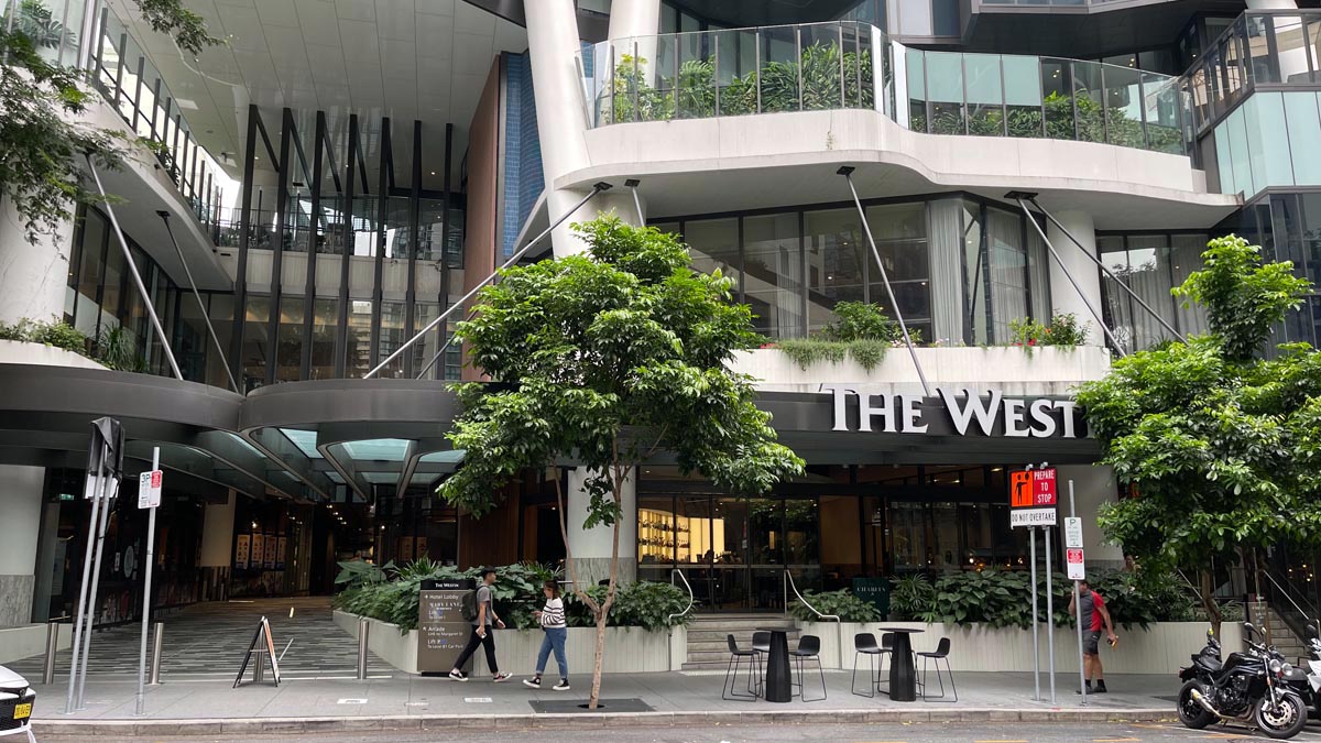 a building with a tree and people walking by