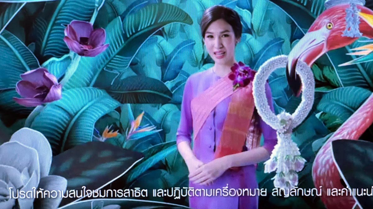 a woman in purple dress standing in front of a large flamingo