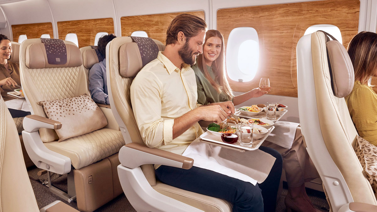 a man and woman sitting in a plane eating food