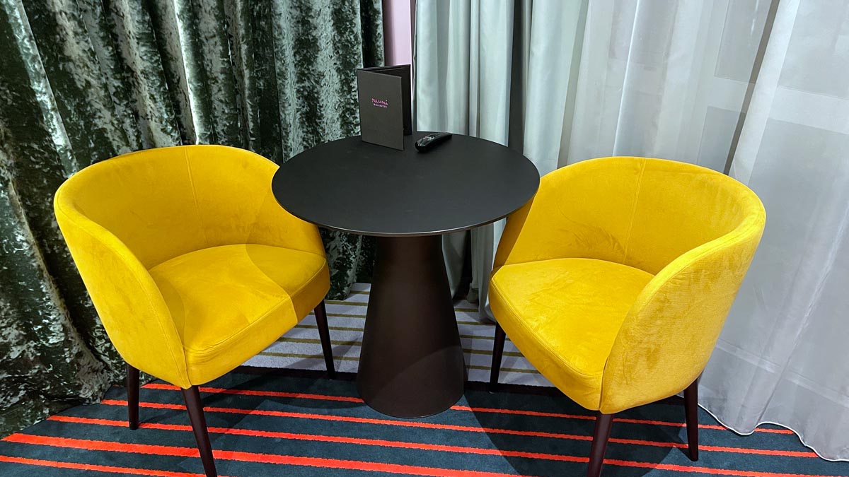 a table with a black box on top and two yellow chairs