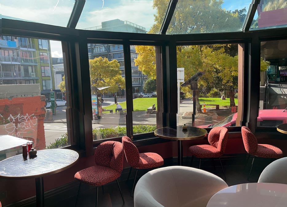 a room with tables and chairs and a view of a street and trees