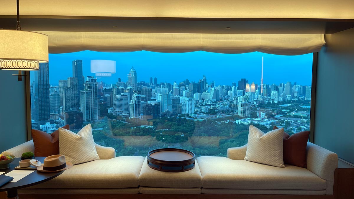 a couch with a table and a city view through a window