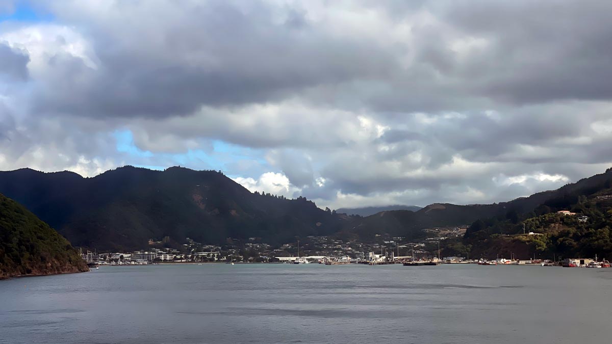 a body of water with buildings and mountains in the background