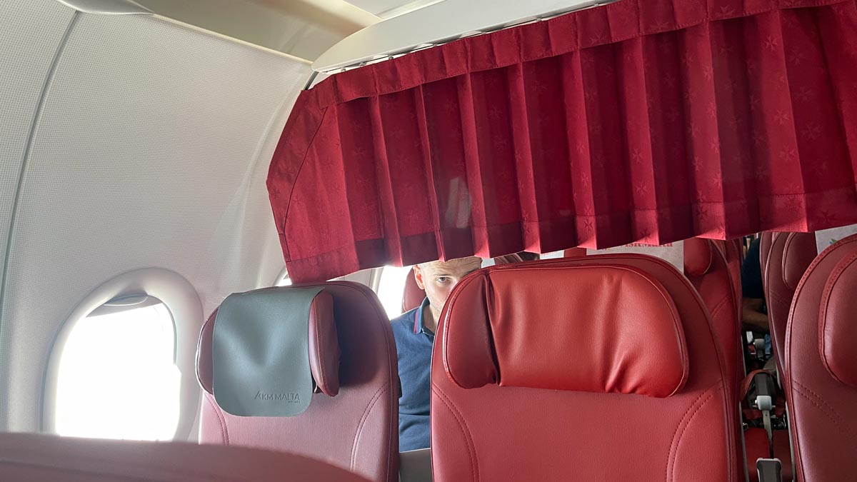 a man sitting in a plane with red curtains