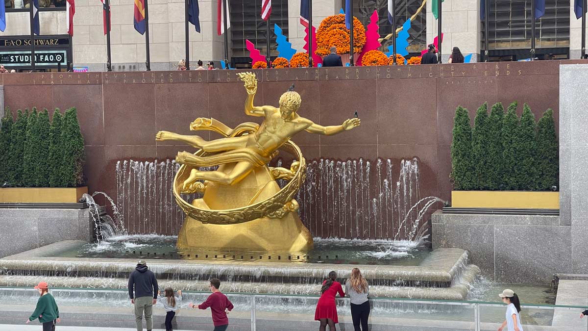 a statue of a man in a circle with a fountain and people