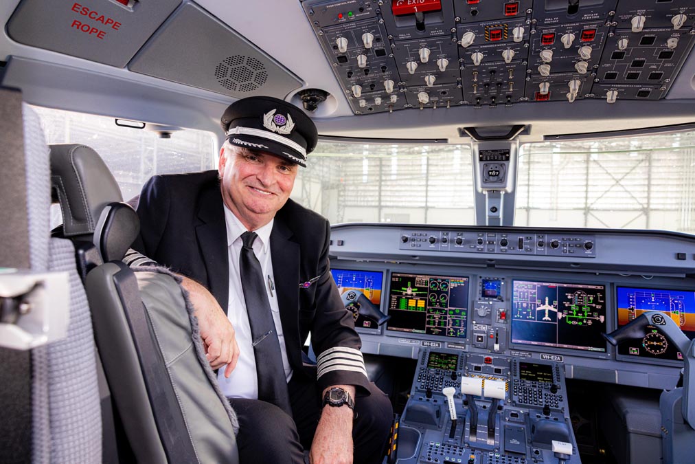 a man in a uniform sitting in a cockpit of an airplane