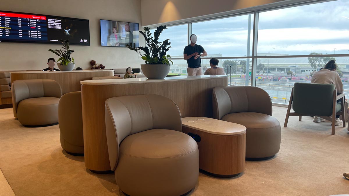 a man standing at a counter in a room with chairs and a plant