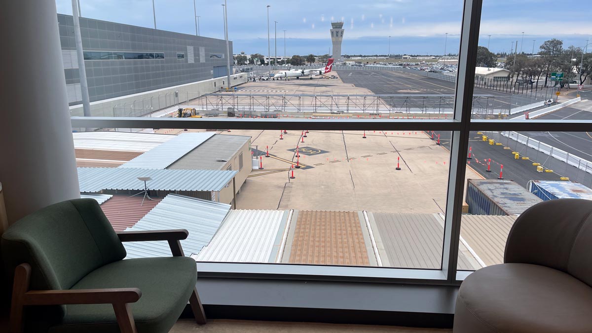 a window with a chair and a plane in the background