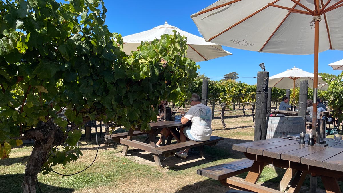 a man sitting at a picnic table under umbrellas