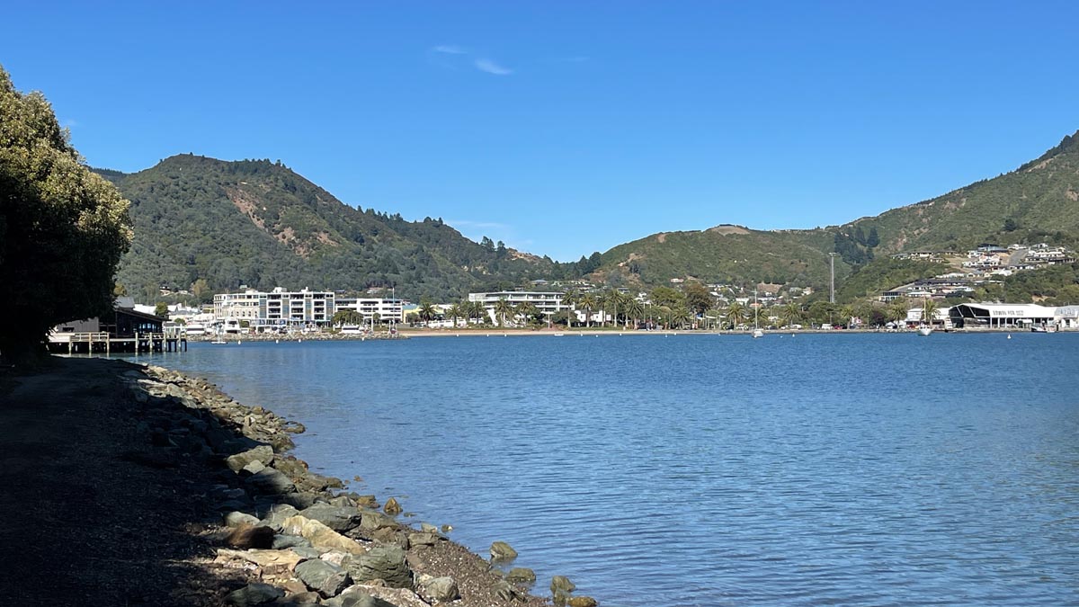 a body of water with buildings and hills in the background